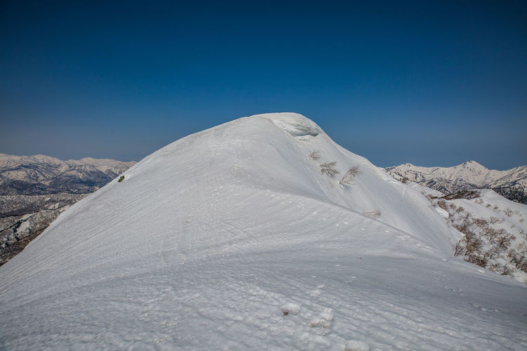 Scenic view of snowcapped mountains against clear blue sky
