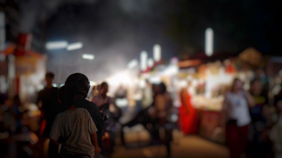 Crowd on illuminated street in city at night
