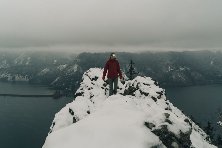 A young woman stands on the top of a snowy point in the columbia gorge