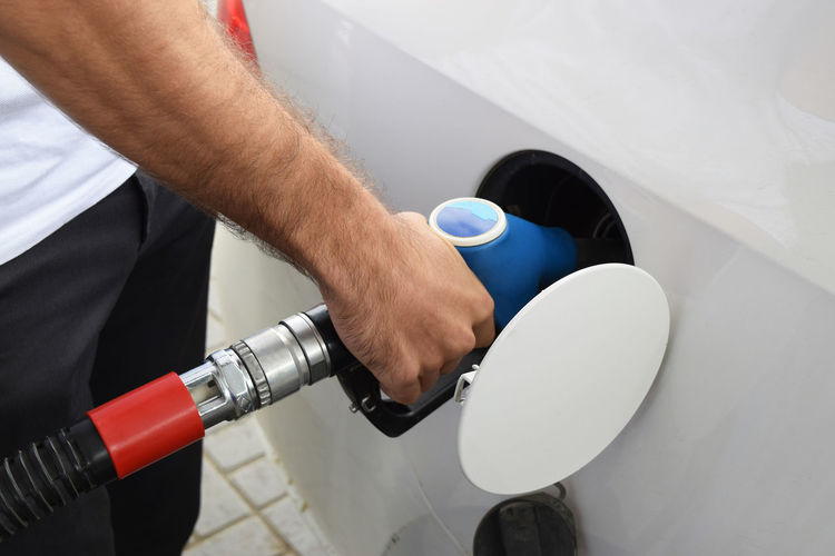 Midsection of man refueling car at gas station
