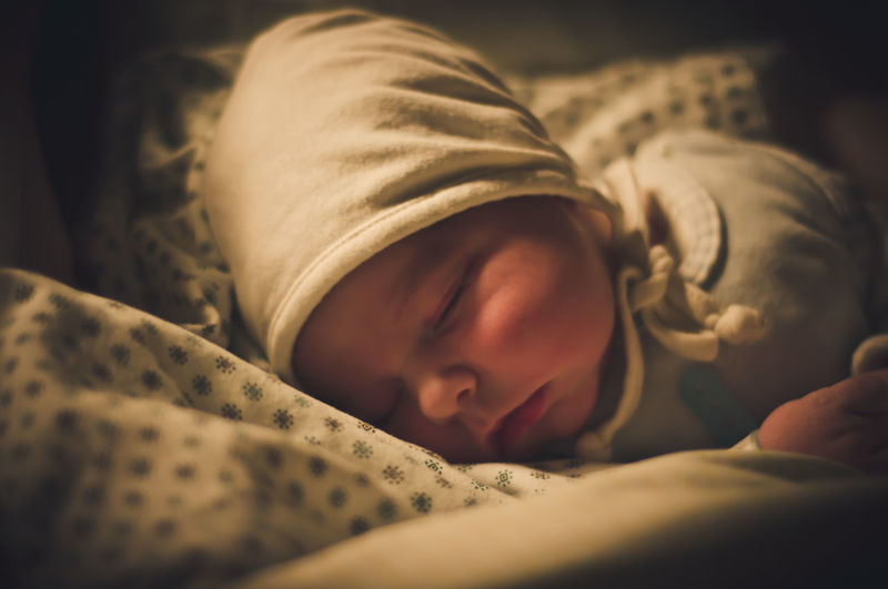 Cute baby boy sleeping on bed at home