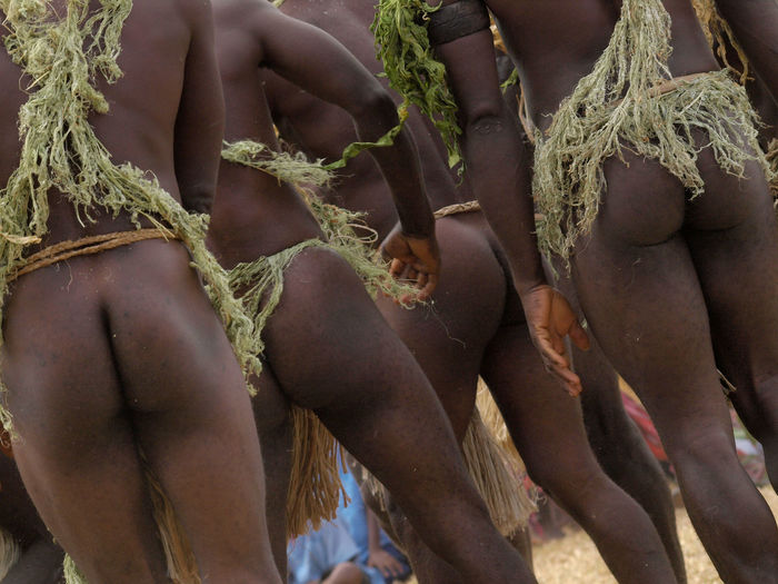 Rear view of naked men standing on field during ceremony