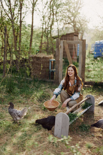 Happy woman feeding chicken in farm