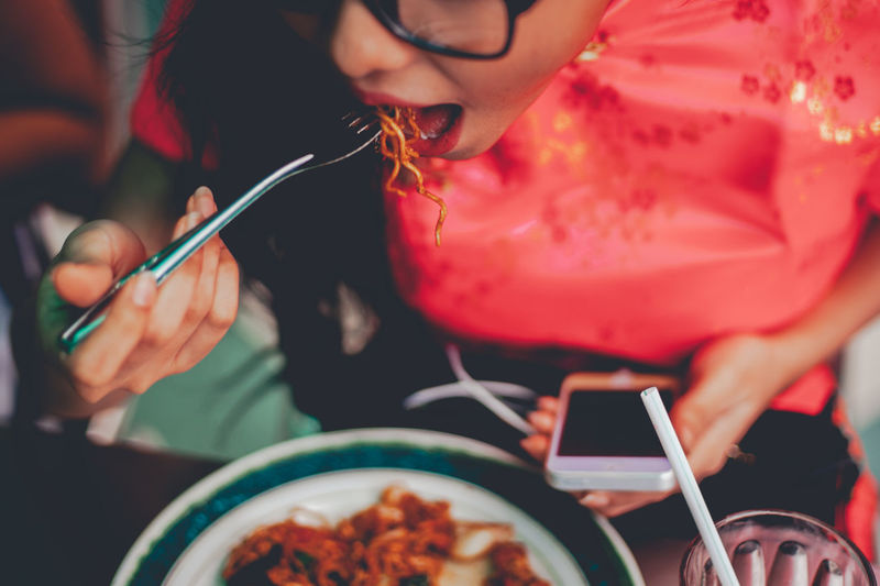 Midsection of woman eating noodles while sitting at table