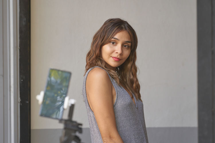 Portrait of young woman standing against wall