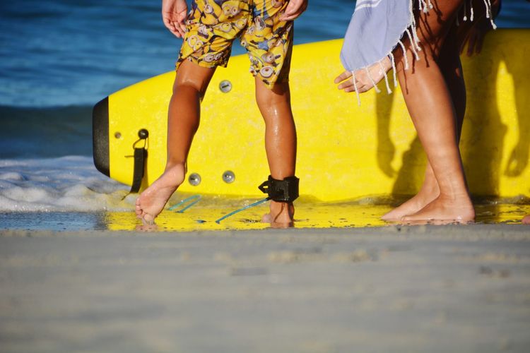 Low section of people standing in sea