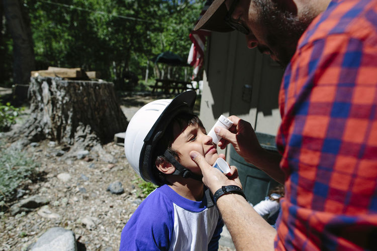 Father applying medicine on son's nose at inyo national forest