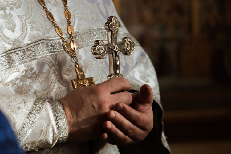 Midsection of priest holding cross in church
