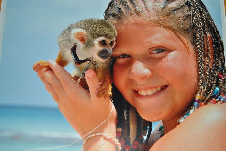 Portrait of happy girl holding squirrel monkey at beach