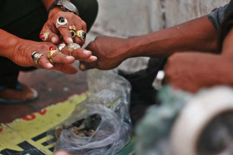 Close-up of male vendor selling rings to customer at market