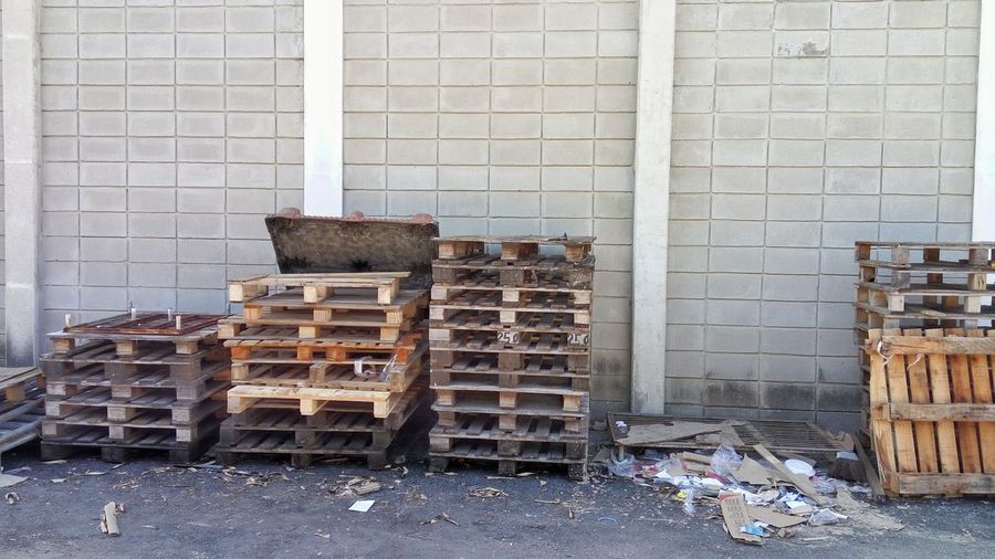 Wooden pallets on footpath against wall