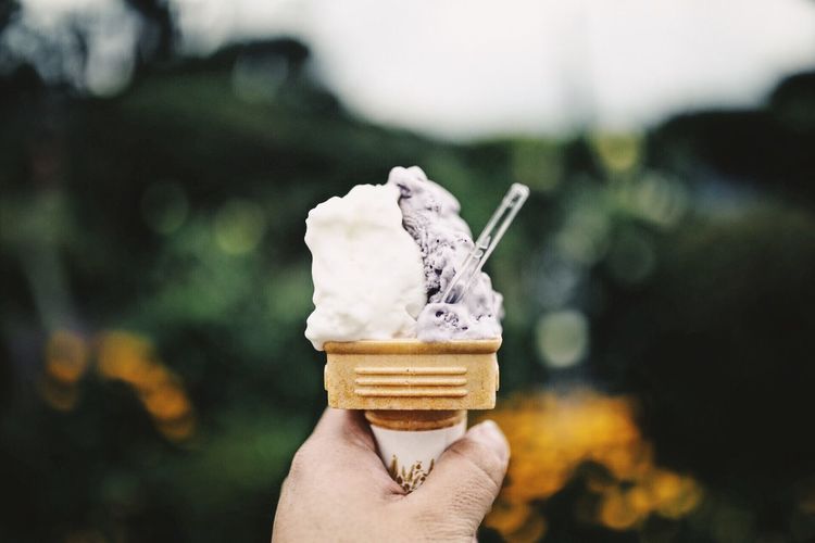 Cropped hand holding ice cream cone outdoors