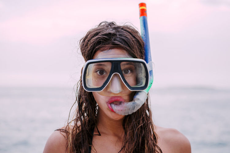 Young woman with diving goggles and snorkel pulling funny faces