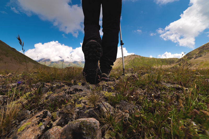 Close-up of boots while hiking on a trail in the mountains. man walking in sports shoes overlooking