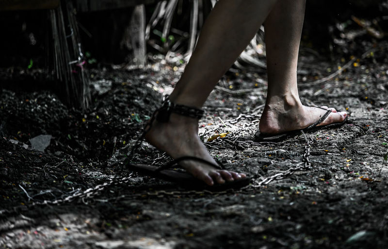 Low section of woman legs trapped with chain in forest