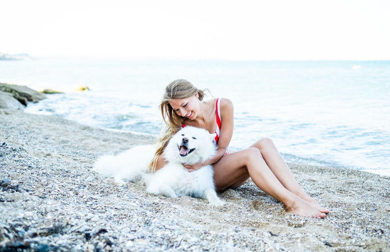 Girl in a swimsuit with a dog on the beach