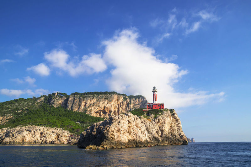 Red lighthouse on the rocky coastline of capri island