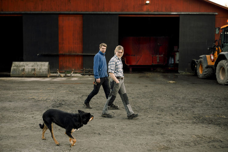 Farmers with dog walking together outside factory
