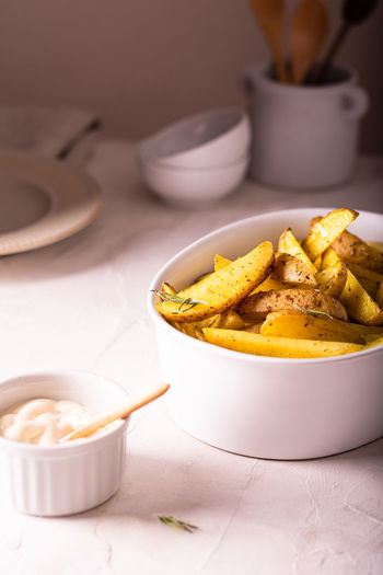 Delicious slices of baked potatoes with rosemary and oil in a ceramic bowl