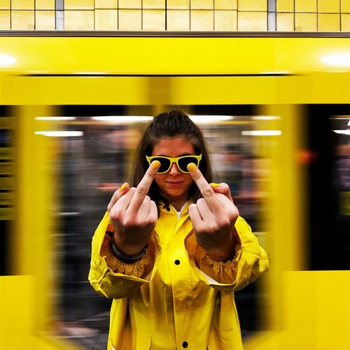 Woman showing middle finger against yellow light trail