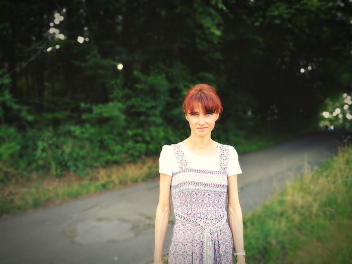 Portrait of young woman standing against trees
