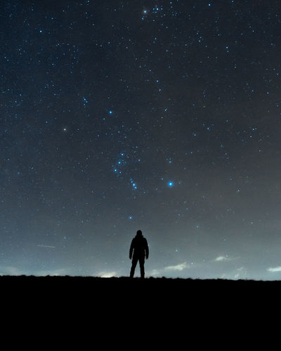 SILHOUETTE MAN STANDING ON FIELD AGAINST SKY