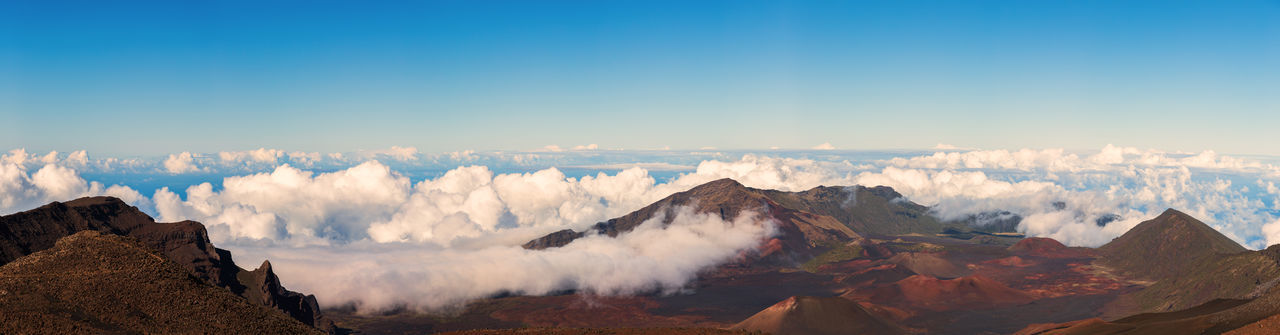 Panoramic view of mountains with cloudscape against clear sky