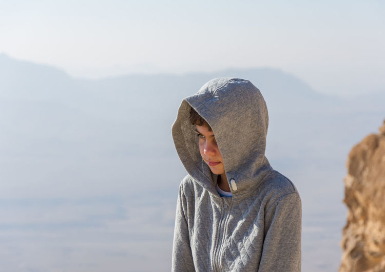 Close-up of boy wearing hood on mountain against sky