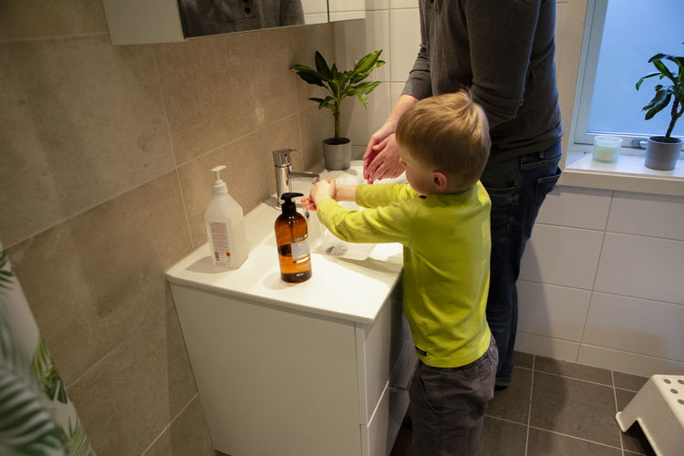 Rear view of boy standing in bathroom at home