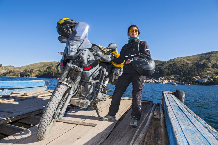 Woman and her touring motorbike on simple ferry crossing lake titicaca