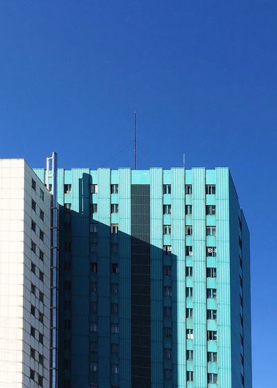 Low angle view of modern building against clear blue sky