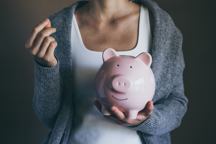 Closeup woman holding happy piggy bank and money guest hand. female saving money.