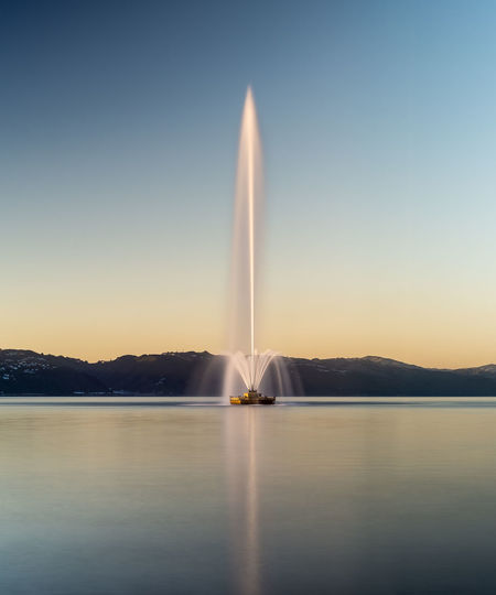 Scenic view of fountain in lake against clear sky