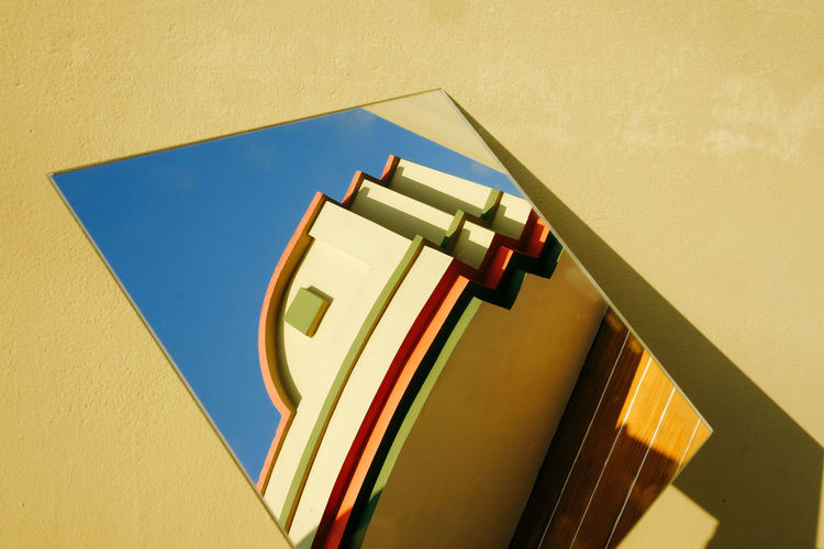 Reflection of building on mirror against yellow wall