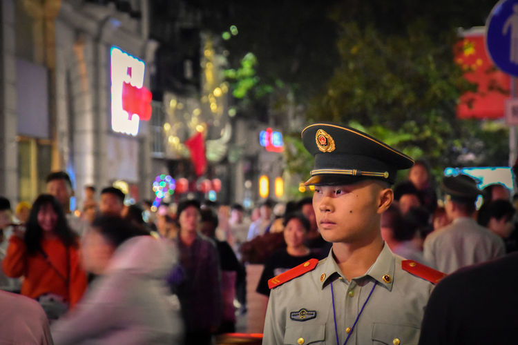 Army soldier wearing uniform while standing in busy street at night