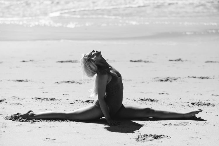 Young woman exercising at shore of beach