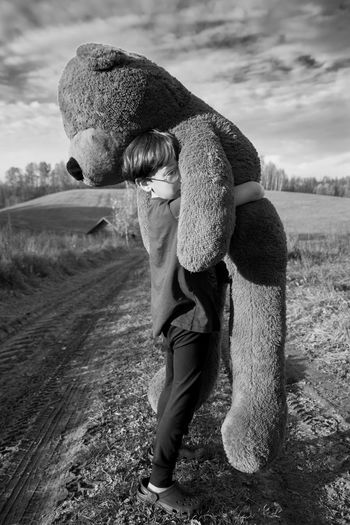 Full length rear view of boy holding a big toy bear