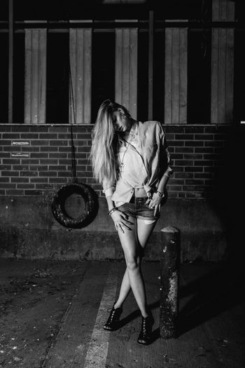 Young woman standing on footpath at night