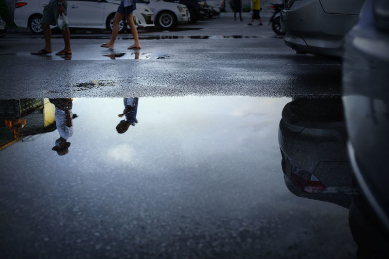 Reflection of people in puddle on city street