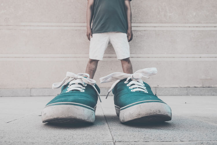 Optical illusion of man wearing green shoes against wall