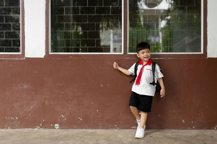 Full length of cute boy standing by school building