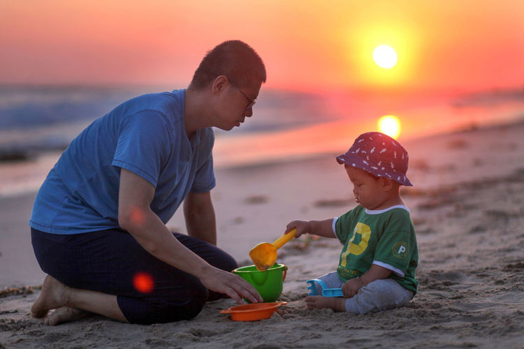 Boy playing with toy on beach during sunset