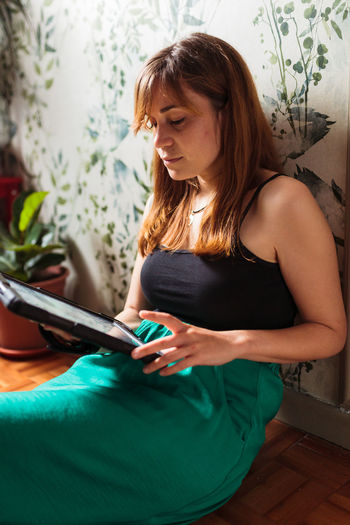 Woman using digital tablet while sitting at home