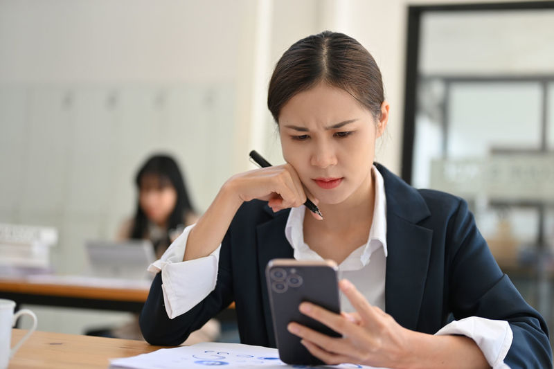 Side view of young woman using mobile phone in office