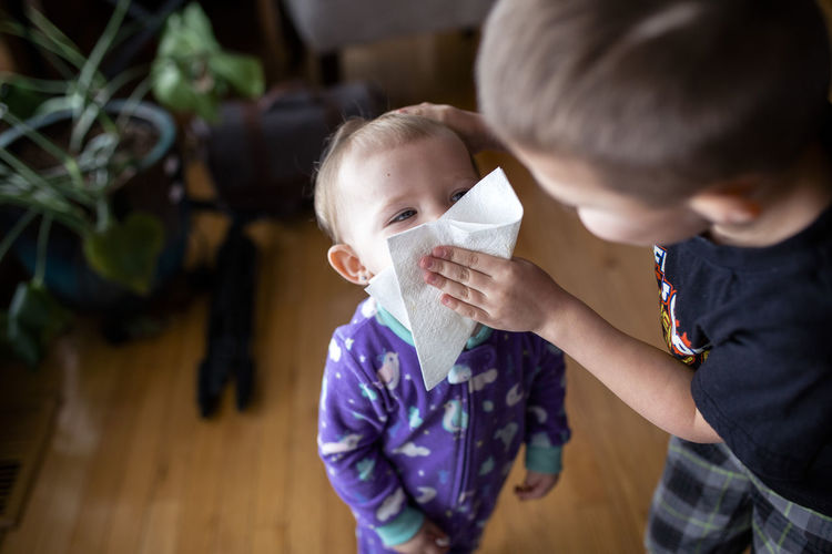 Bother wiping sister's face with facial tissue at home