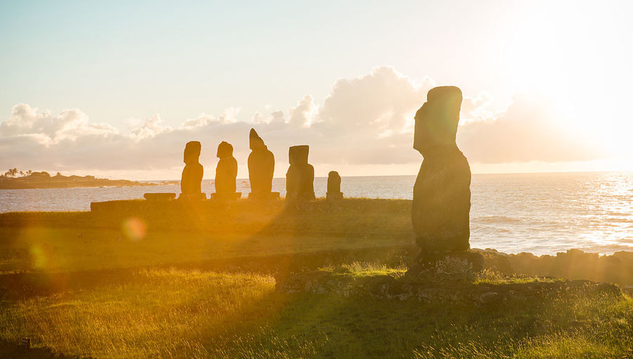 Scenic view of sea against sky during sunset with moai at easter island