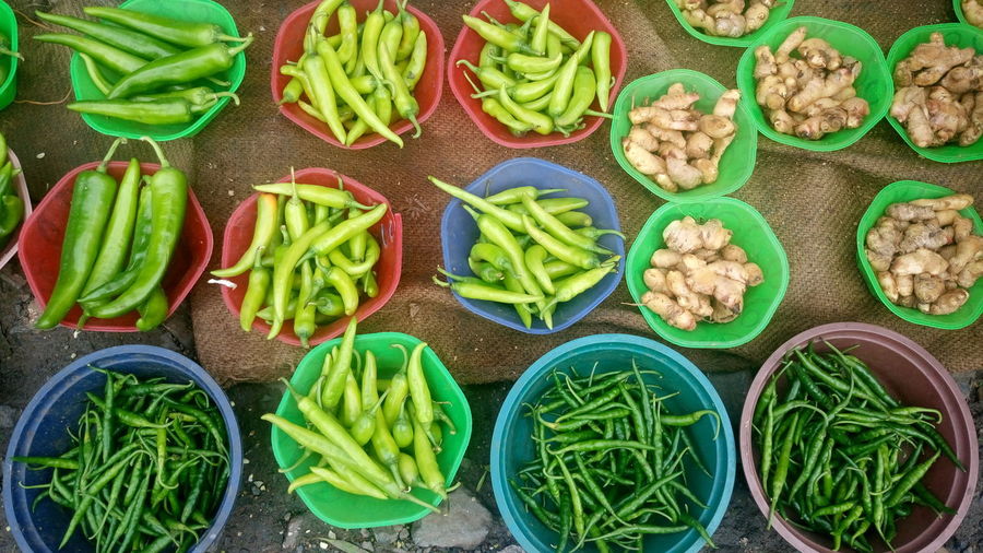 High angle view of green chili peppers in containers at market for sale