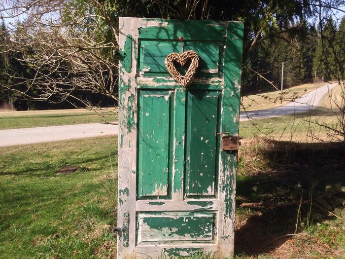 Abandoned door with heart on grassy field