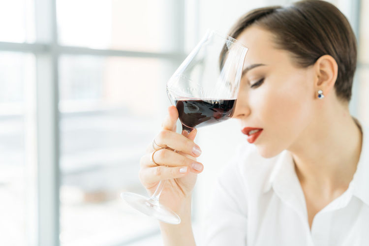 Close-up of young woman drinking wine in office