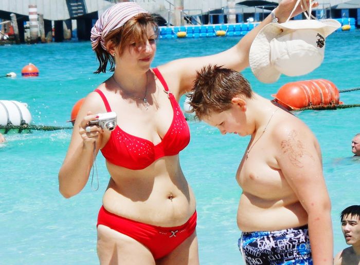 Woman and son standing against swimming pool